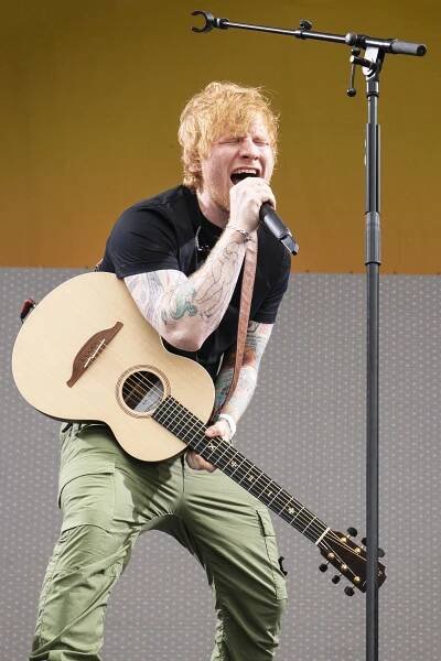 Ed Sheeran performing on stage with an acoustic guitar.