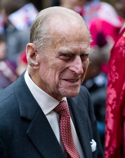 Prince Philip wears a black suit and red tie