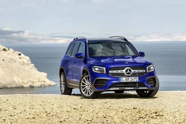 Blue Mercedes-Benz GLB parked on a rocky surface overlooking the ocean.