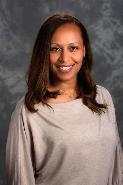 Professional studio portrait of woman in gray sweater against mottled background.