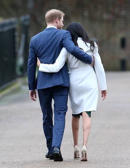 Prince Harry and Meghan Markle facing away from the camera with their arms wrapped around each other in 2017