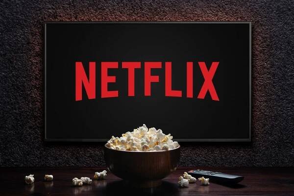 Netflix-Logo auf einem Bildschirm. Davor eine Schüssel mit Popcorn.