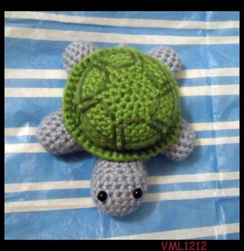 a crocheted turtle laying on top of a blue and white striped bed sheet