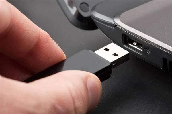 user inserting a USB flash drive into a laptop