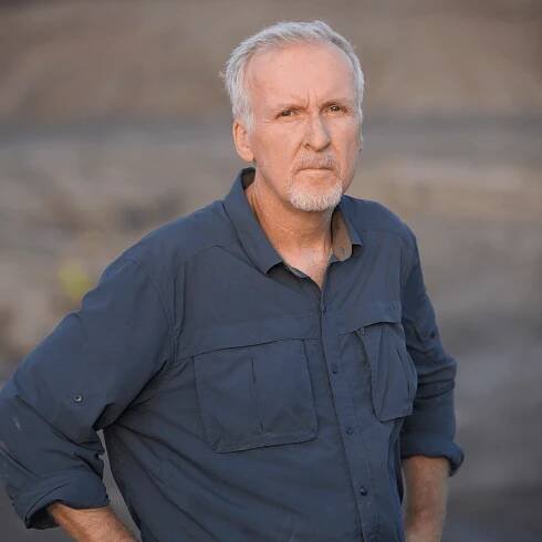Photo of a man, James Cameron, wearing a blue button up shirt and jeans. 
