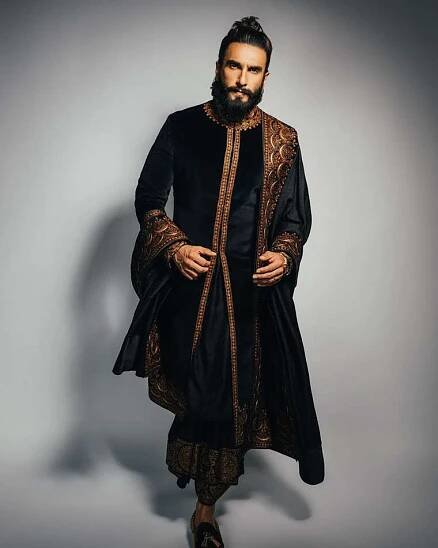 Ranveer Singh wearing a black sherwani with gold metallic border on it.