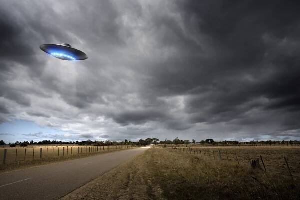Illustration of a UFO over a country road.
