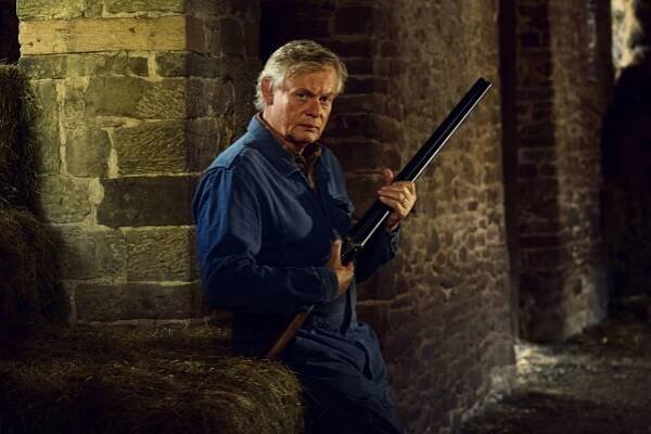Martin Clunes as Nathan Williams holding a shotgun in a barn.
