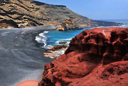 a view of a beach with red rocks and the ocean at Holiday Apartment C Lanzarote in Arrecife