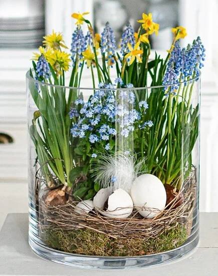 a vase filled with flowers and eggs on top of a table