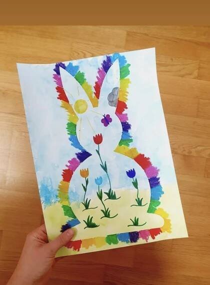 a person holding up a paper with an image of a bunny on it