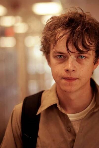 a young man with brown hair and blue eyes is looking at the camera while wearing a backpack
