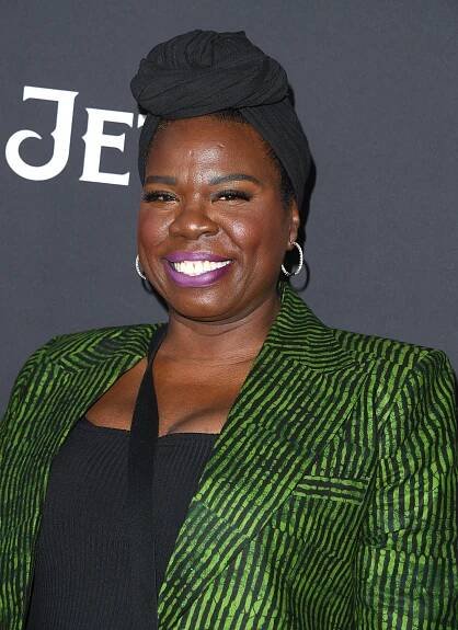 Leslie Jones on red carpet wearing a green and black striped blazer with a black top and a head wrap
