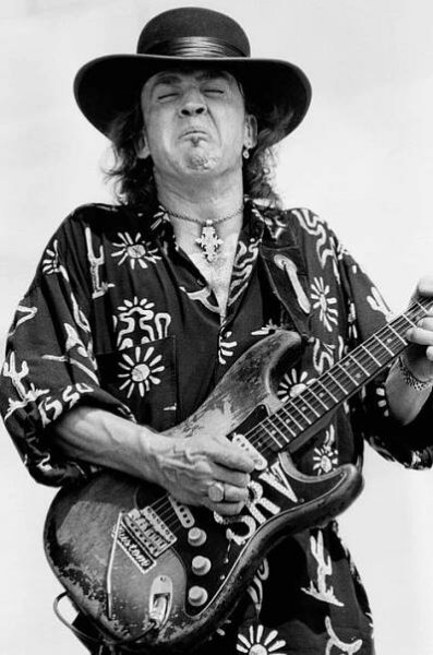 a man wearing a hat and playing an electric guitar