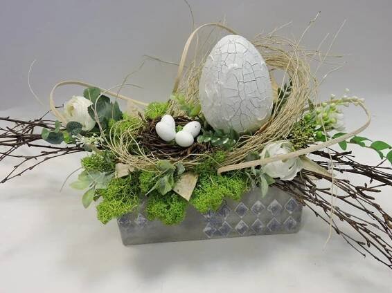 an arrangement of branches, flowers and eggs in a vase