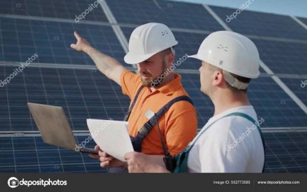 Zblízka inženýři používají notebook a projektový plán na solární farmě ve speciální uniformě stojící rozhlédnout diskutovat o instalaci slunečných baterií elektrické prostředí. Zelená pracovní místa