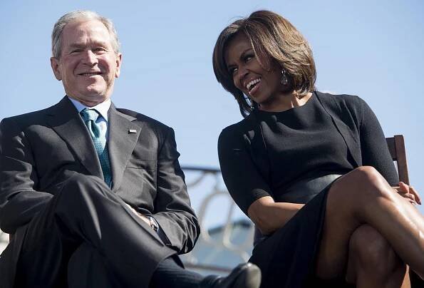 Former US President George W. Bush smiles as he speaks with First Lady Michelle Obama during an event marking the 50th Anniversary of the Selma to Montgomery civil rights marches at the Edmund Pettus Bridge in Selma, Alabama, March 7, 2015.