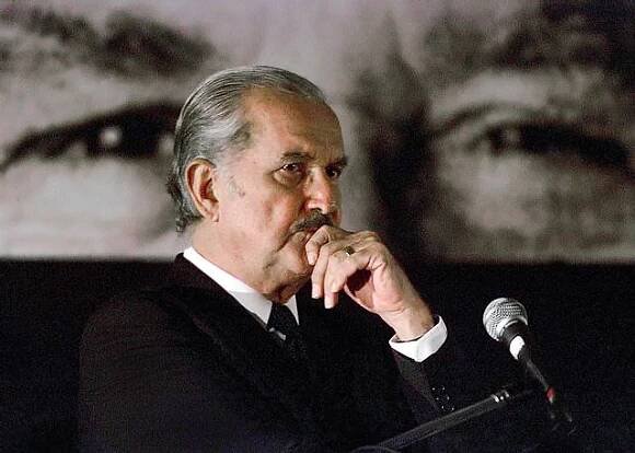 Carlos Fuentes listens to questions during a UNICEF conference, "Latin America between two millenniums, challenges and hopes." Guatemala City, August 28, 2001. The eyes shown on the poster behind Mr. Fuentes are his own. (Photo by Jorge Silva © Reuters/CORBIS)