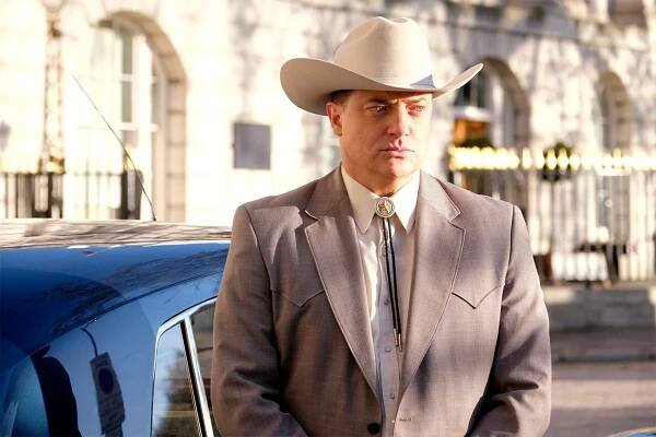 Image may contain Clothing Apparel Human Person Hat Coat Suit Overcoat Tie Accessories Accessory and Cowboy Hat