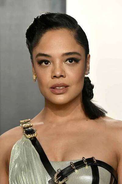 Tessa Thompson with a low, short ponytail and one-shoulder dress