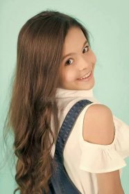 Kid model with long healthy brunette hair. Girl with smile on cute face on blue background. Beauty, look, hairstyle. Youth, skincare, health. Happy child, childhood concept.