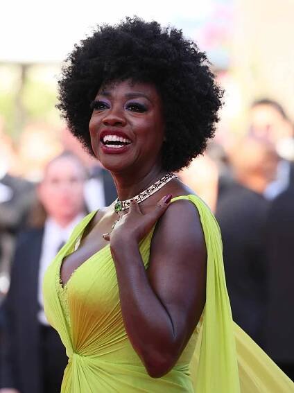 Viola Davis with a curly tapered cut while wearing a statement necklace and lime green-yellow dress