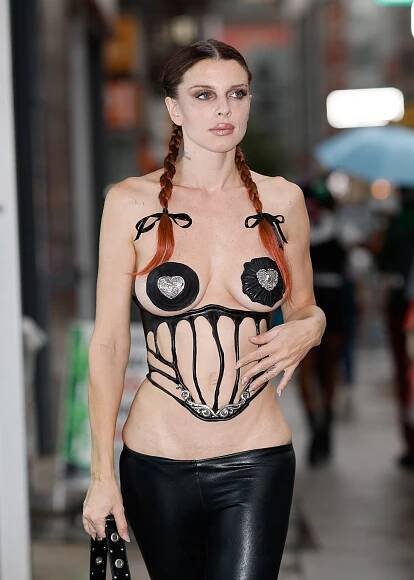 Julia Fox wearing a belly-baring corset and black leather pasties. 