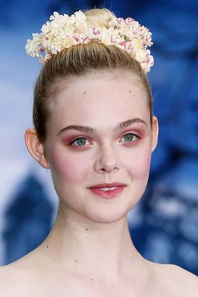 "Maleficent"-Star Elle Fanning präsentiert nicht nur ein avantgardistisches Augen-Make-up, sondern unterstreicht ihren elfengleichen Look auch mit zartgelben Kunstblumen in ihrer Hochsteckfrisur.