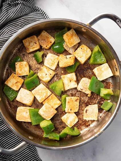 Marinated paneer, bell peppers, are cooking over the pan.