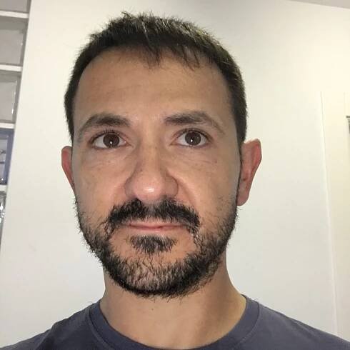 Carlos Cámara is a white man in his 40's with short black hair and a grey t-shirt with a joomla badge pinned.
