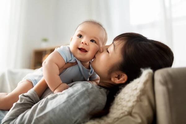happy mother kissing little baby son at home