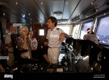 Captain Steffen Freidrich discusses the operation of the expedition cruiser Orion with passengers during a customary bridge tour Stock Photo