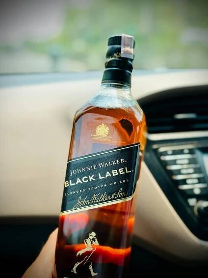 Free Elegant Johnnie Walker Black Label whisky bottle set in car interior. Stock Photo