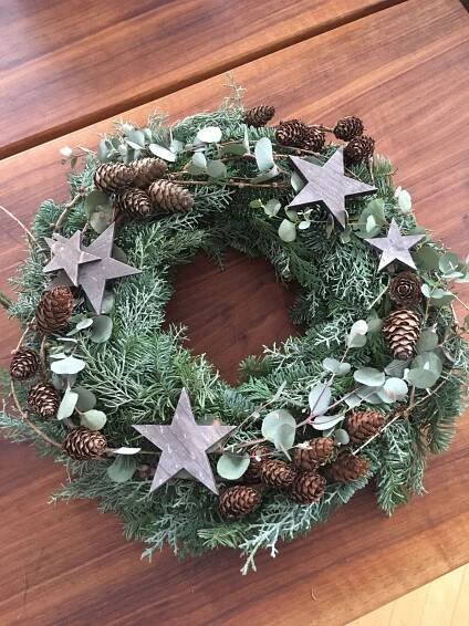 a christmas wreath with silver stars and greenery