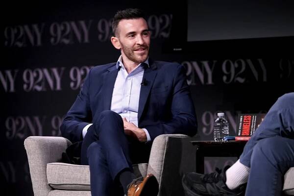 Brian Tyler Cohen, a Democratic influencer, wearing a dark-blue suit as he sits at an event in New York. 