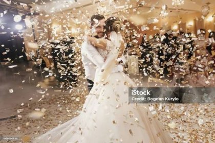 Nádherná nevěsta a stylový ženich tančí pod zlatými konfety na svatební hostině. Šťastný svatební pár provádí první tanec v restauraci. Romantické chvíle - Bez autorských poplatků Svatba - Oslava Stock fotka