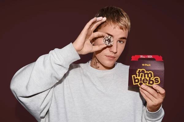 Justin Bieber holding up a Timbit Timbiebs to his eye.