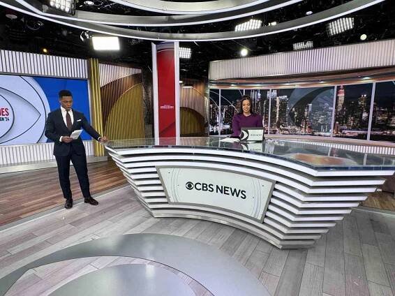 Two TV anchors read on a CBS set. 