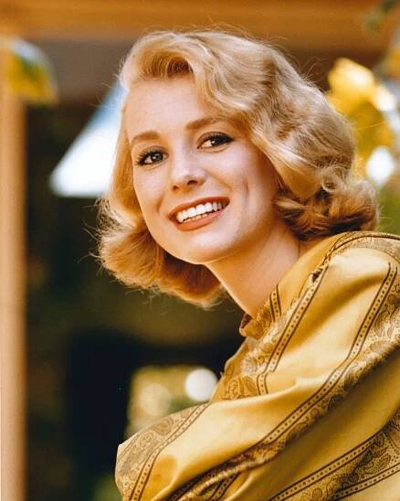 A woman in a yellow dress is smiling.