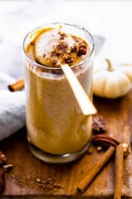 a spoon scooping some of a pumpkin shake out of a tall glass cup