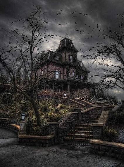 an old house with stairs leading up to it and dark clouds in the sky above