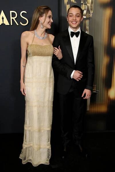 a woman in a white dress stands next to a man in a tuxedo