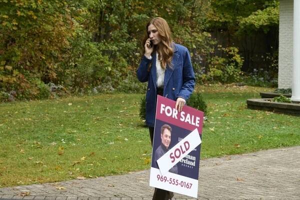 Susan Ireland (Sarah Levy) holds a "SOLD" For-Sale lawn sign on SurrealEstate Episode 301.