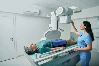 mužský pacient ležící na lůžku, zatímco zdravotní sestra nastavuje moderní rentgenový přístroj pro skenování nohy nebo kolena pro zranění a zlomeniny - rentgenové záření monitorovací zařízení - stock snímky, obrázky a fotky