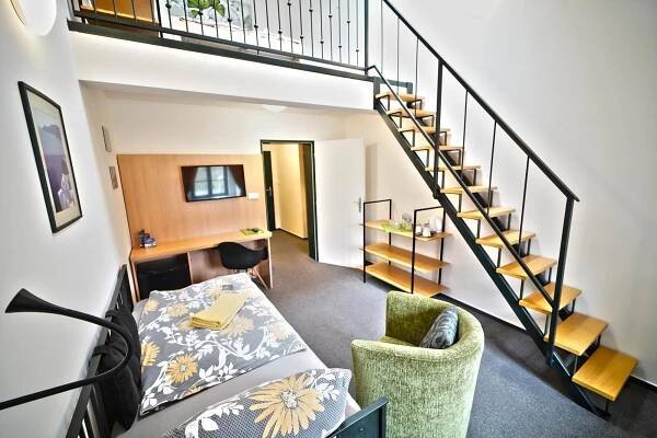 a living room with a bed and a staircase at Wellness hotel Lihovar in Třemošnice