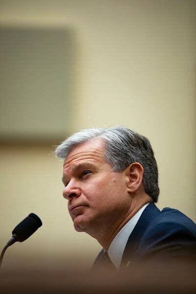A close-up, profile photo of Christopher A. Wray, in front of a microphone.