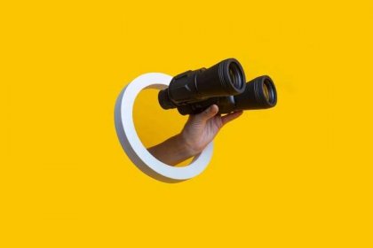 ženská ruka držící dalekohled v díře na žlutém pozadí. - triedr optický přístroj - stock snímky, obrázky a fotky