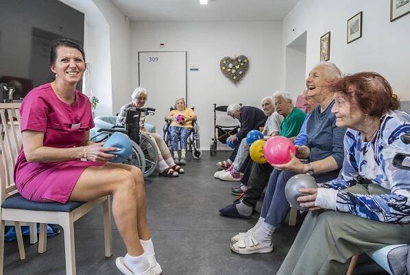 Senioři v domově Senlife při sportovních aktivitách s pečovatelkou.