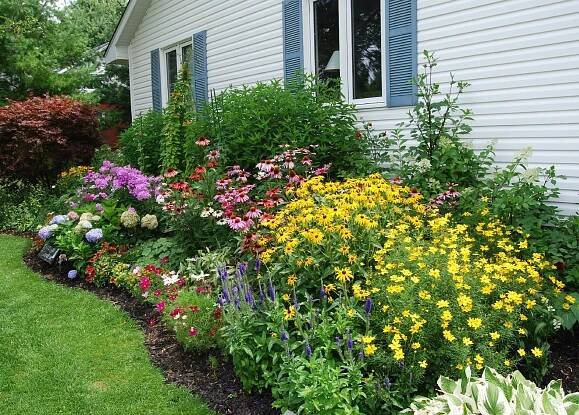 a flower garden in front of a white house