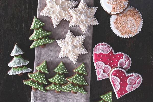 decorated cookies are on a napkin next to some christmas trees and heart shaped cookie cutters